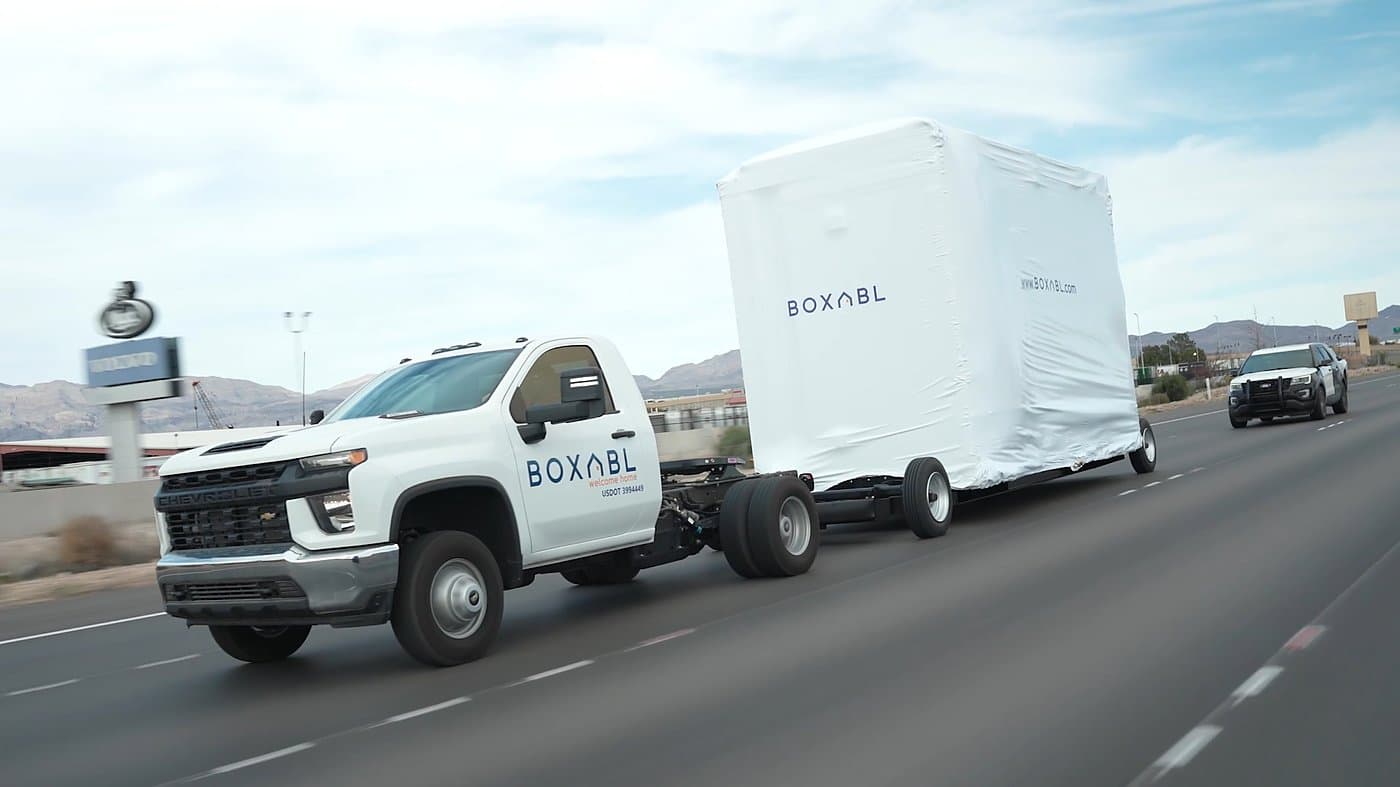 A wrapped BOXABL home being transported by truck